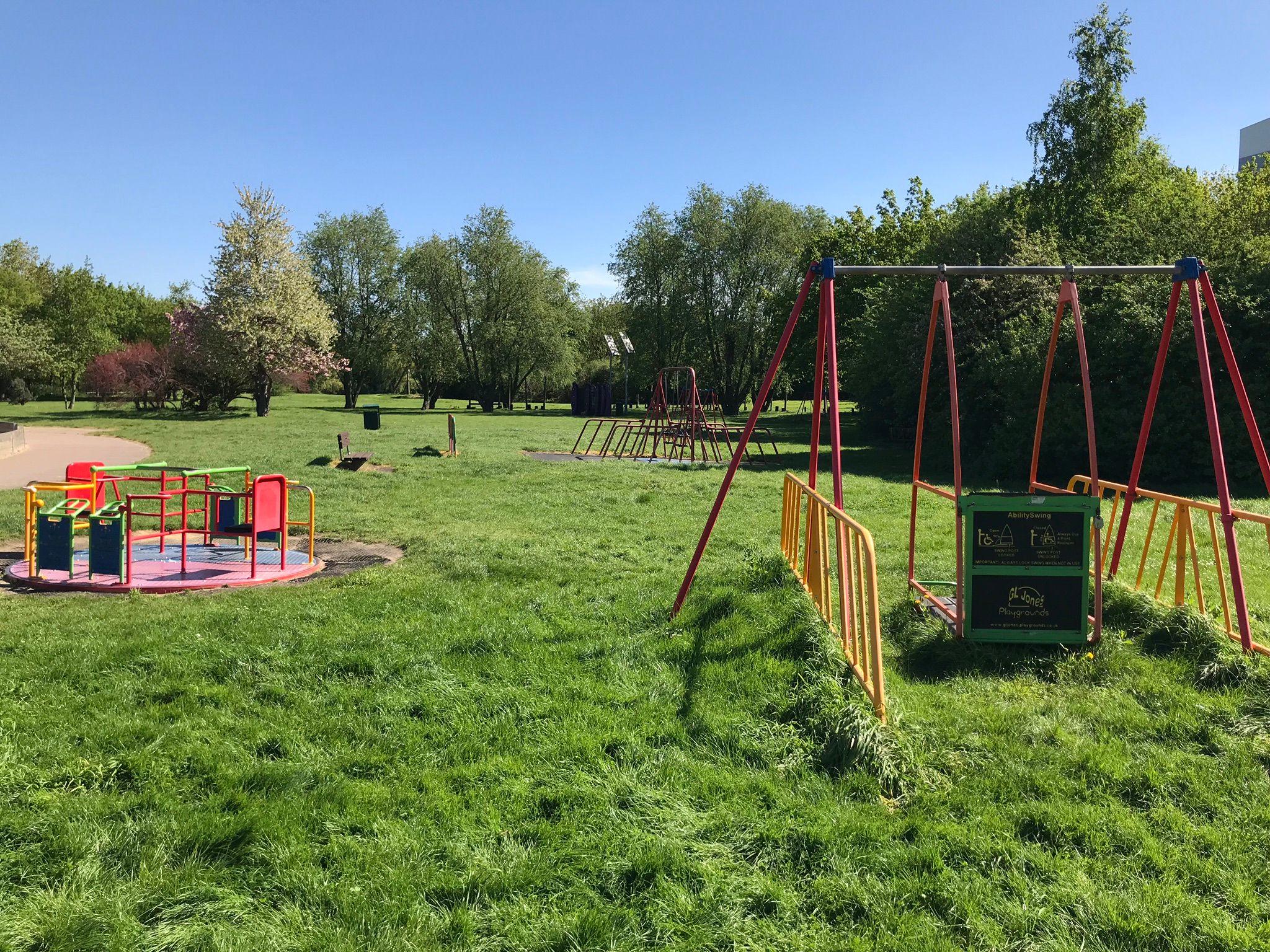 Play equipment on the grass including accessible swing and roundabout.