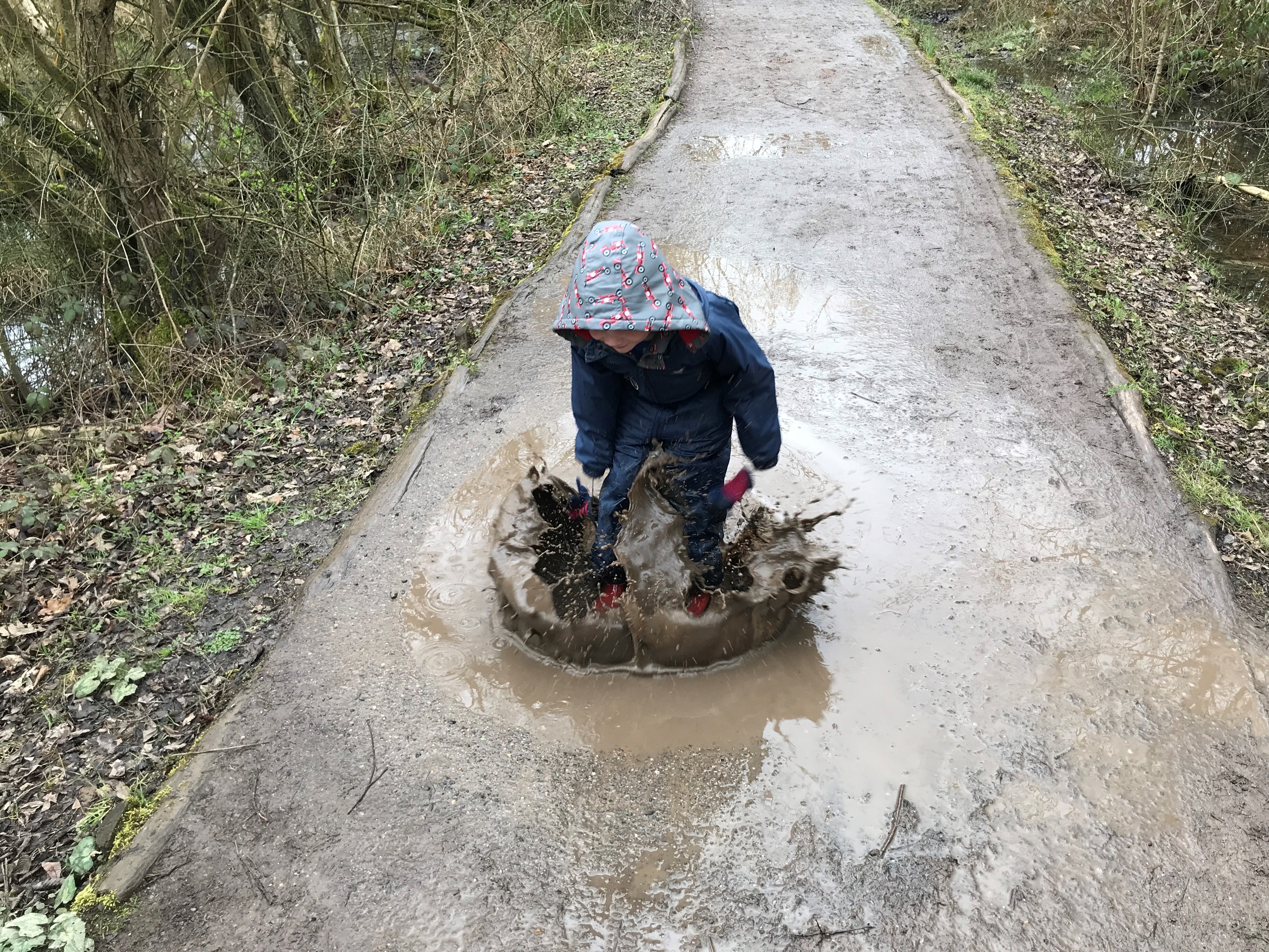 Boy jumping in a muddy puddle at Shorne Country park