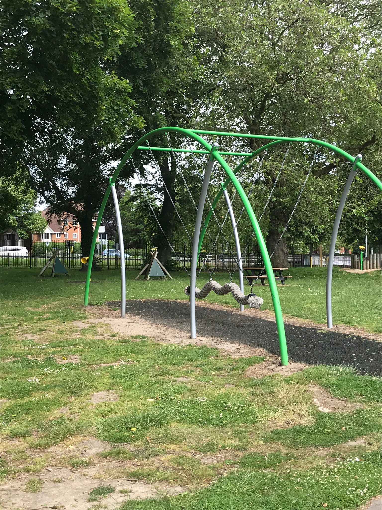 long rope swing in the fore-ground and climbing frames can be seen in the shade of the trees